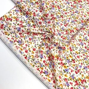 May include: White fabric with a small floral print in shades of red, yellow, blue, and green.