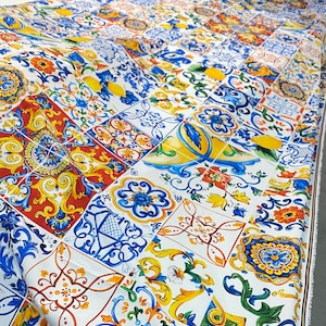 Pu&ograve; includere: Tessuto bianco con un motivo ripetuto di piastrelle colorate in stile italiano. Le piastrelle presentano motivi floreali, forme geometriche e limoni in tonalit&agrave; di blu, giallo, rosso e verde.