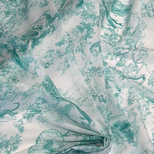 May include: White fabric with a teal green toile de Jouy design. The fabric features a repeating pattern of trees, animals, and figures in a forest setting. The fabric is folded, showing the texture and drape of the material.