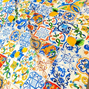 Pu&ograve; includere: Tessuto bianco con un motivo colorato di piastrelle blu, gialle, arancioni e verdi. Le piastrelle presentano disegni floreali e forme geometriche.