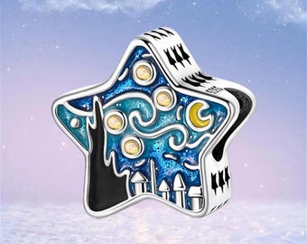 May include: A star-shaped silver charm bead featuring an enamel inlay of a night sky scene with swirling blue patterns, a yellow crescent moon, and small circular yellow accents. The design includes a black silhouette of a building structure.