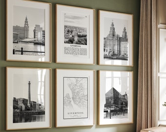 May include: A living room with a green wall and a light brown couch. There are six black and white framed prints on the wall, featuring images of the city of Liverpool, England. The prints include a map of the city, a view of the waterfront, and a close-up of the Liver Building.