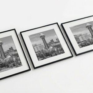 Puede incluir: Tres impresiones en blanco y negro enmarcadas de un paisaje urbano con una torre alta con una parte superior esférica. Las impresiones están dispuestas en diagonal, mostrando la obra de arte enmarcada sobre un fondo blanco. Los marcos tienen un diseño simple y moderno.