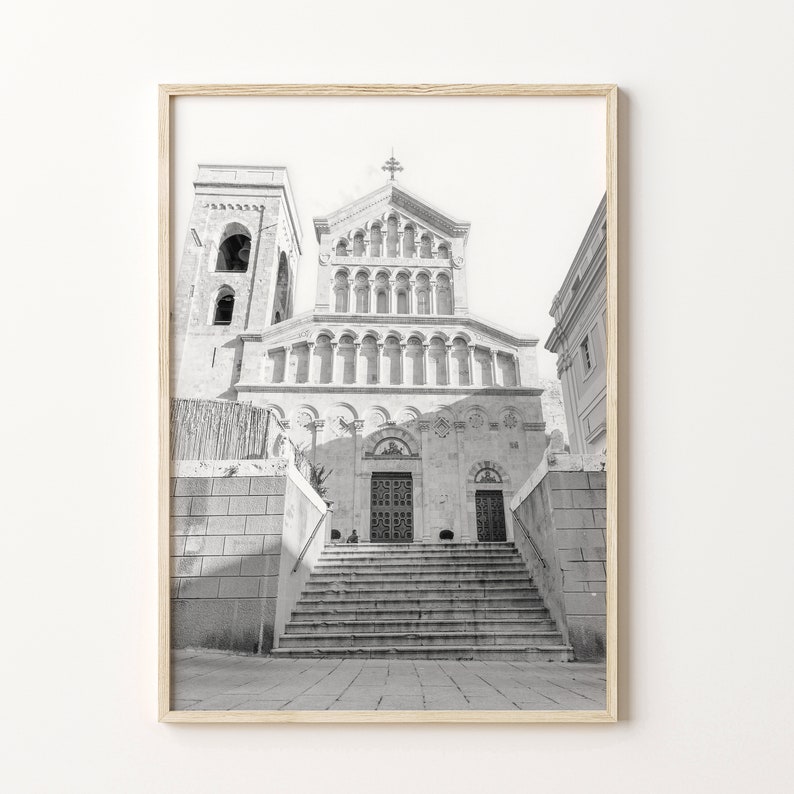 May include: Black and white photograph of a stone building with a large arched doorway and steps leading up to it. The building has a tall tower on the left side and a smaller tower on the right side.