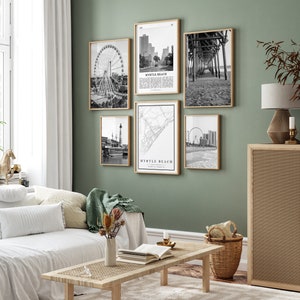 May include: A living room with a white couch and a coffee table. The wall is green and has five black and white framed prints of various scenes from Myrtle Beach, South Carolina. The prints include a Ferris wheel, a pier, a map, and a cityscape.