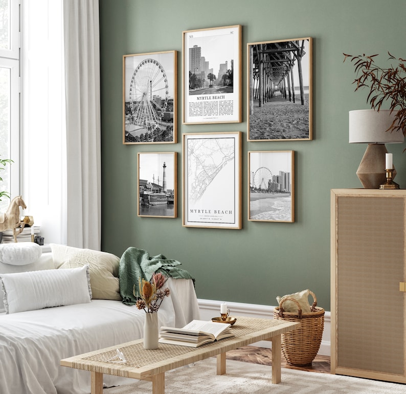 May include: A living room with a white couch and a coffee table. The wall is green and has five black and white framed prints of various scenes from Myrtle Beach, South Carolina. The prints include a Ferris wheel, a pier, a map, and a cityscape.