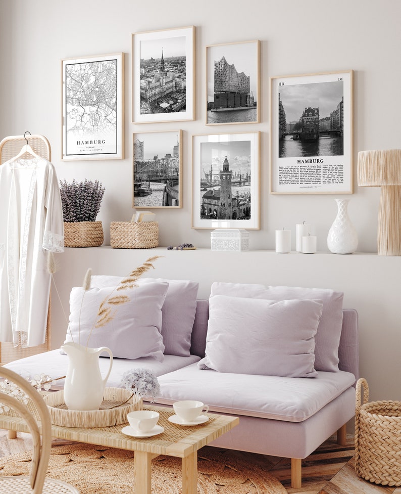 May include: A living room with a light purple sofa, a coffee table, and a wall with black and white framed prints of Hamburg, Germany. The prints include a map, a cityscape, and a building.