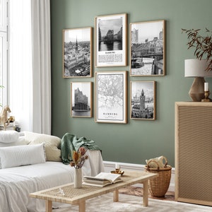 May include: A set of five black and white framed prints featuring various images of Hamburg, Germany. The prints are arranged in a grid pattern on a green wall. The prints include a map of Hamburg, a view of the city skyline, and a view of the Elbe River.