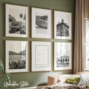 May include: A set of six black and white framed prints featuring images of Trinidad and Tobago. The prints include a map of the island, a building, a beach scene, and a landscape. The prints are arranged in a grid pattern on a green wall.