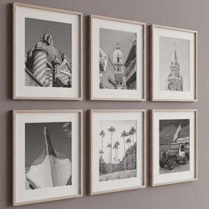 May include: Six framed black and white photographs with light wood frames. The images depict architectural details, a boat, and a jeep. The photographs are displayed on a neutral-coloured wall.