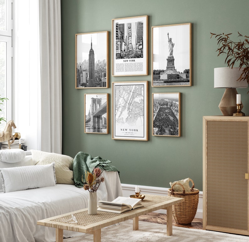 May include: A set of six framed black and white prints depicting New York City landmarks. The images show the Empire State Building, Times Square, the Statue of Liberty, Brooklyn Bridge, a map, and Central Park. The frames are a light wood colour.