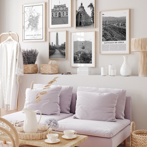 Puede incluir: Un interior de sala de estar con un sof&aacute; de color morado claro, una mesa de caf&eacute; y una pared decorada con impresiones enmarcadas en blanco y negro de paisajes urbanos y edificios. Las impresiones presentan el texto "Santiago de Chile".