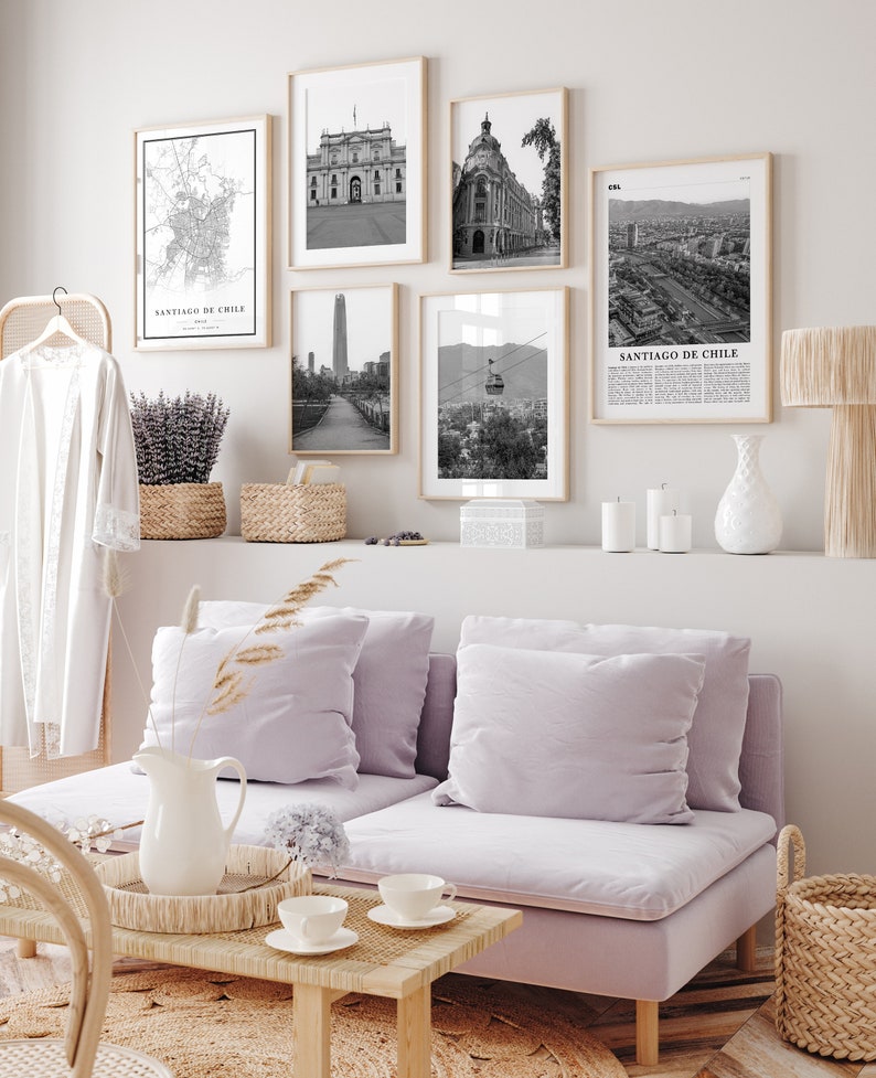 Puede incluir: Un interior de sala de estar con un sof&aacute; de color morado claro, una mesa de caf&eacute; y una pared decorada con impresiones enmarcadas en blanco y negro de paisajes urbanos y edificios. Las impresiones presentan el texto "Santiago de Chile".
