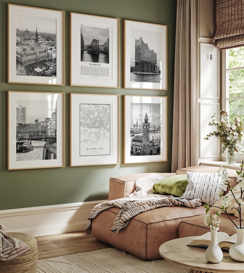 May include: A living room with a light green wall and a couch with a brown leather seat and a striped throw blanket. There are six black and white framed photos on the wall, all depicting different scenes of the city of Hamburg, Germany. The photos include a map of the city, a view of the city skyline, and a view of a building with a clock tower.