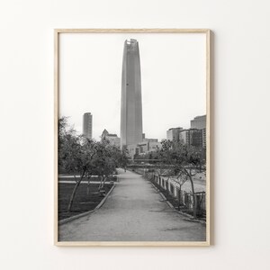 Puede incluir: Una fotograf&iacute;a en blanco y negro de un rascacielos alto en una ciudad. El rascacielos est&aacute; rodeado de otros edificios y &aacute;rboles. Una pasarela pavimentada conduce al edificio.