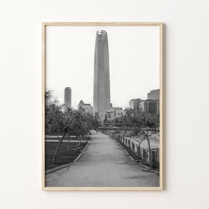 Puede incluir: Una fotograf&iacute;a en blanco y negro de un rascacielos alto en una ciudad. El rascacielos est&aacute; rodeado de otros edificios y &aacute;rboles. Una pasarela pavimentada conduce al edificio.