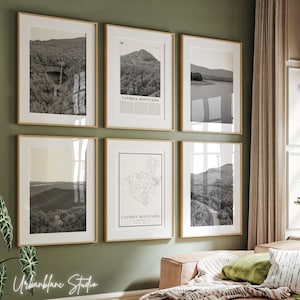 Puede incluir: Un conjunto de seis impresiones en blanco y negro enmarcadas de las montañas Catskill. Las impresiones están dispuestas en una cuadrícula en una pared verde. Las impresiones presentan diferentes vistas de las montañas, incluyendo un mapa, un primer plano de un pico de montaña y una vista panorámica.