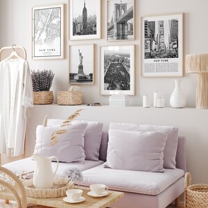 May include: A living room with framed black and white prints of New York City landmarks, such as the Empire State Building and Brooklyn Bridge. The room includes a lilac sofa, a wooden coffee table, and various decorative elements.