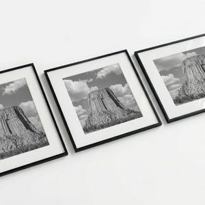 May include: Three framed black and white photographs of a mountain landscape. Each photo is in a black frame with a white mat. The mountain is the focal point, set against a cloudy sky.