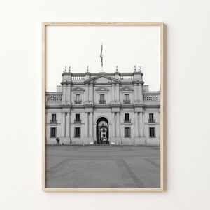 Puede incluir: Una fotograf&iacute;a en blanco y negro de un edificio grande y ornamentado con una bandera ondeando en la parte superior. El edificio tiene una gran arcada en el centro y muchas ventanas. El edificio est&aacute; rodeado de una zona pavimentada.