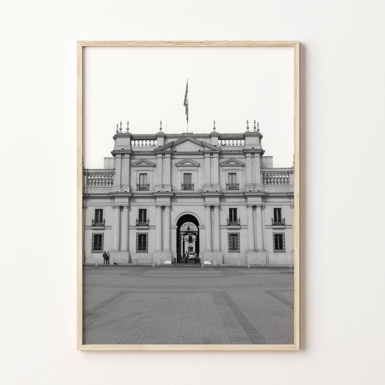 Puede incluir: Una fotograf&iacute;a en blanco y negro de un edificio grande y ornamentado con una bandera ondeando en la parte superior. El edificio tiene una gran arcada en el centro y muchas ventanas. El edificio est&aacute; rodeado de una zona pavimentada.