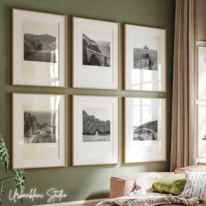 Pode incluir: Uma parede de galeria com seis fotografias em preto e branco emolduradas de paisagens costeiras. As molduras são de madeira natural e têm um design simples e moderno.