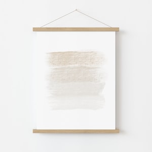May include: A framed print with a beige and white abstract watercolor design. The print is hanging on a white wall.