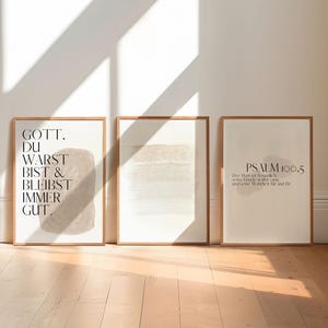 May include: Three framed prints with a minimalist design. The left print features a beige abstract shape with the text "GOTT. DU WARST BIST & BLEIBST IMMER GUT." The middle print features a beige abstract shape. The right print features a beige abstract shape with the text "PSALM 100.5."