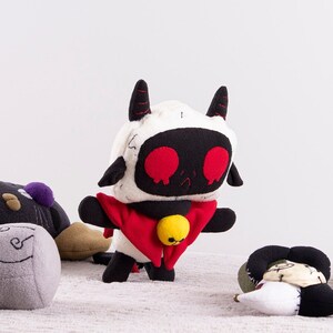 May include: Five plush toys, including a black and white character with red eyes and a red cape, a gray and white character with a swirl design, a black and gray character with a purple detail, a black and blue character with yellow buttons, and a white and black character with a black and white design.