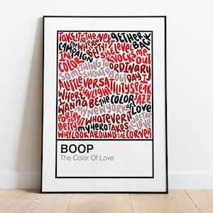 May include: A framed art print with a black border. The artwork features a collage of words in red, black, and gray, with the word "BOOP" at the bottom. The text "The Color Of Love" is below "BOOP".