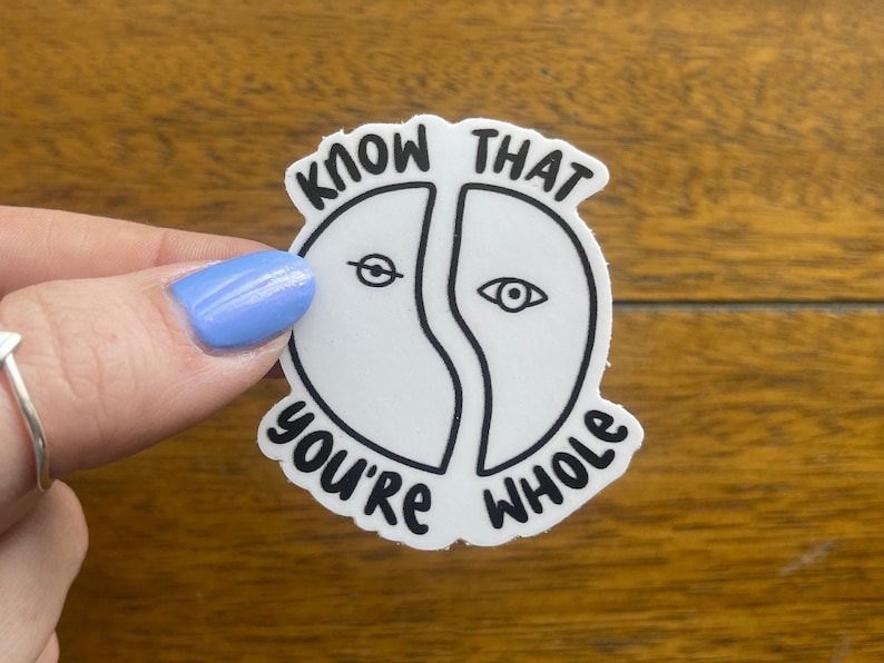 Puede incluir: Pegatina blanca con texto negro y un dibujo de l&iacute;nea negra de dos ojos. El texto dice "Know that you're whole".