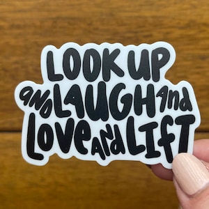May include: White sticker with black text that reads "Look Up and Laugh and Love and Lift".