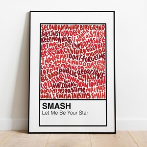 May include: A framed art print with a white background and a black border. The print features the word "SMASH" and the phrase "Let Me Be Your Star" in a white rectangle at the bottom. The main design is a red, handwritten-style text.