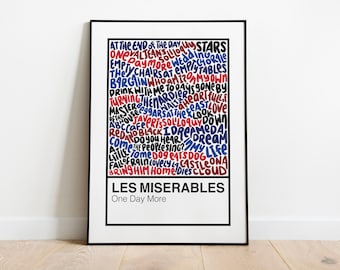 May include: A black framed poster with a white background featuring a word cloud of lyrics from the musical Les Miserables. The words are in red, blue, and black and are arranged in a vertical column. The title "Les Miserables" is at the bottom of the poster in black text, with the subtitle "One Day More" below it.