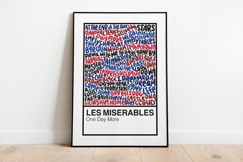Pode incluir: Um p&ocirc;ster emoldurado em preto com fundo branco que apresenta uma nuvem de palavras de letras da obra musical Les Mis&eacute;rables. As palavras est&atilde;o em vermelho, azul e preto e est&atilde;o dispostas em uma coluna vertical. O t&iacute;tulo "Les Mis&eacute;rables" est&aacute; na parte inferior do p&ocirc;ster em texto preto, com o subt&iacute;tulo "One Day More" abaixo.