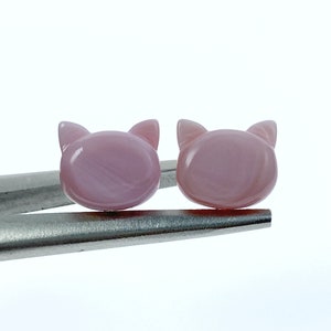 May include: A pair of pink cat-shaped earrings made of mother of pearl.