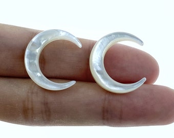 May include: A pair of white crescent moon earrings made of mother of pearl.