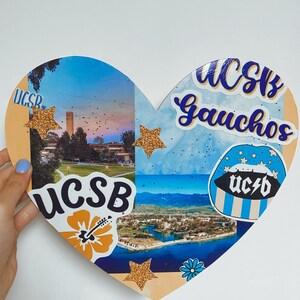 May include: A heart-shaped collage with a blue and white background. The collage features images of the University of California, Santa Barbara (UCSB) campus, including the iconic Storke Tower. The collage also includes several stickers with the UCSB logo and the words "Gauchos" and "UCSB".
