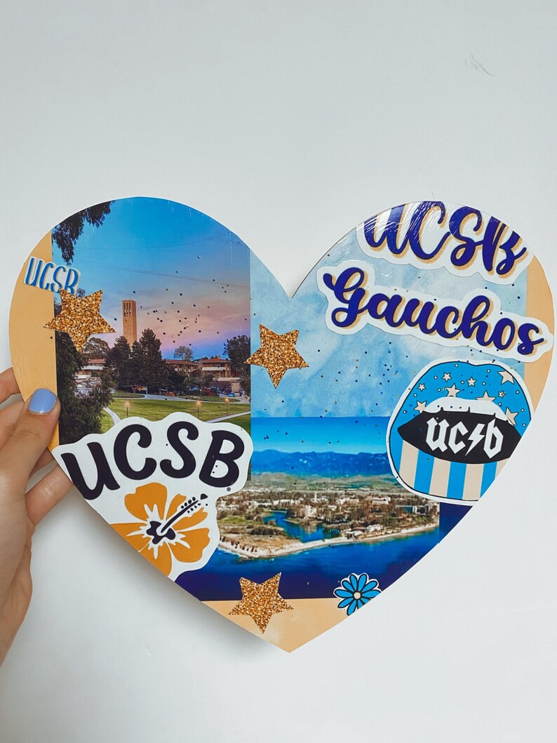May include: A heart-shaped collage with a blue and white background. The collage features images of the University of California, Santa Barbara (UCSB) campus, including the iconic Storke Tower. The collage also includes several stickers with the UCSB logo and the words "Gauchos" and "UCSB".