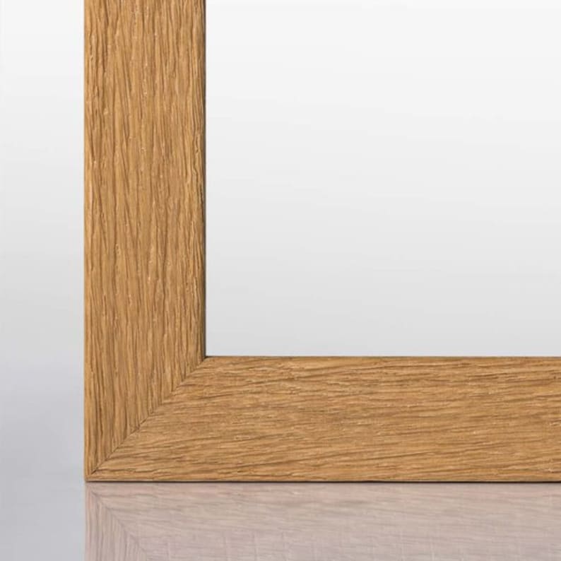 May include: A close-up of a wooden picture frame with a natural wood finish. The frame has a simple, rectangular design and a smooth surface.