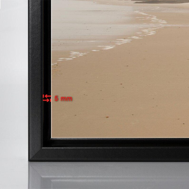 May include: A black framed canvas print of a beach scene with white footprints in the sand. The frame is 5 mm wide.