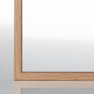 Könnte beinhalten: Nahaufnahme der Unterkante eines Holzbildrahmens. Der Rahmen besteht aus hellbraunem Holz mit natürlicher Maserung.