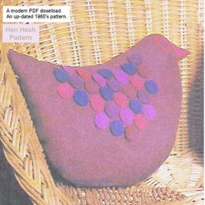 May include: A mauve-colored, hen-shaped soft toy with colorful felt circles. The text "Hen Hesh Pattern" is visible. The image is set against a woven background, suggesting a vintage or handmade theme. The image also includes the text "A modern PDF download. An up-dated 1960's pattern."
