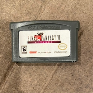 May include: A gray Game Boy Advance cartridge for Final Fantasy VI Advance. The label features the game title in red and white, with the ESRB rating and Nintendo Square Enix branding.