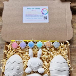 White rabbit, eggs and carrot made from plaster with magnet, paints and brush in a box.