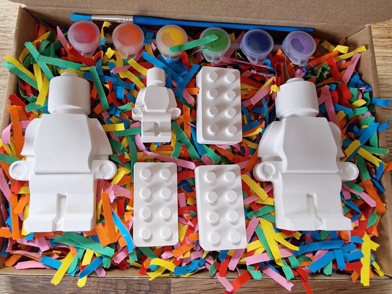 May include: A paint-your-own LEGO&reg; minifigure kit with three white ceramic minifigures, two white ceramic LEGO&reg; bricks, and four small paint pots with red, yellow, green, and blue paint.