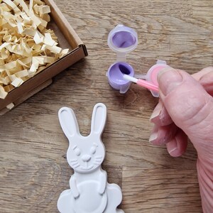 White rabbit and egg made from plaster with magnet, paints and brush in a box.