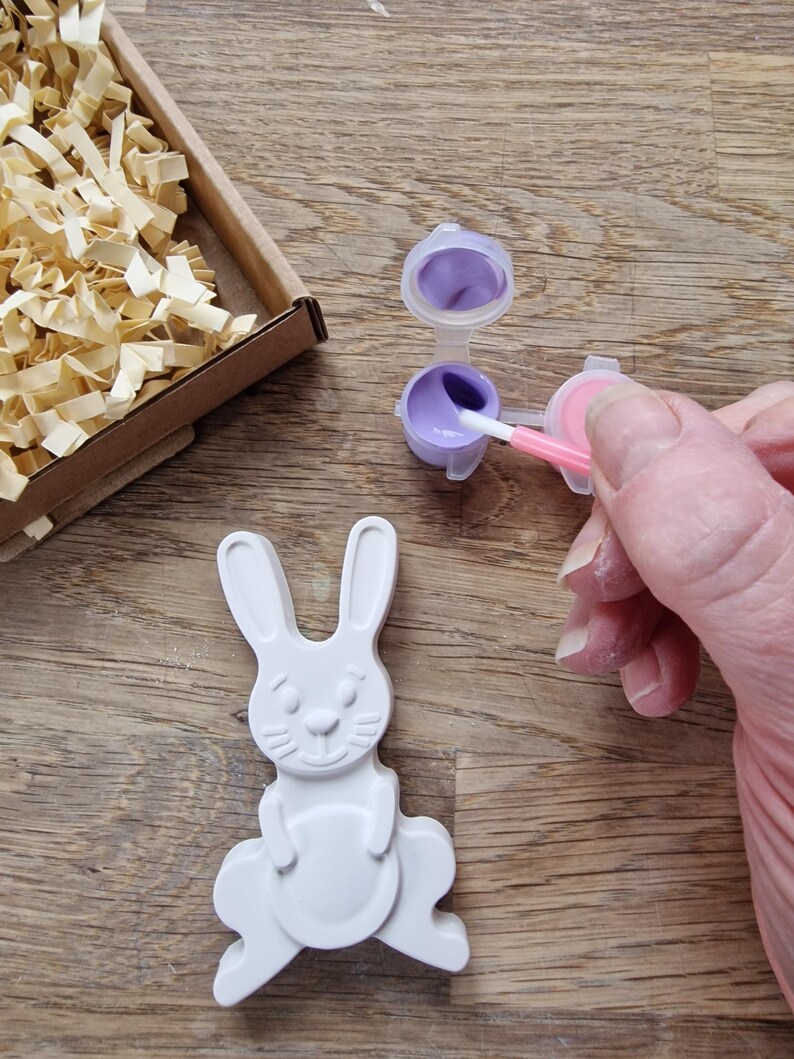 White rabbit and egg made from plaster with magnet, paints and brush in a box.