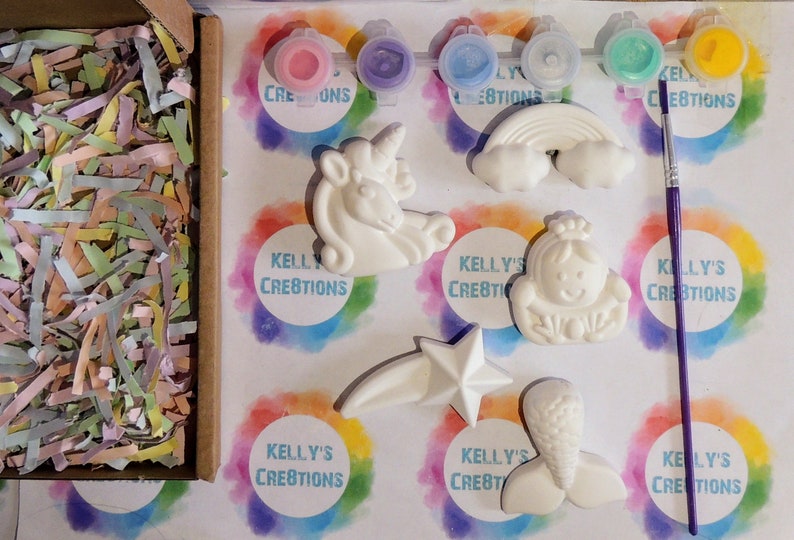 Puede incluir: Un kit de cer&aacute;mica para pintar con seis figuritas de cer&aacute;mica blanca: un unicornio, un arco&iacute;ris, una cola de sirena, una estrella, una princesa y una sirena. El kit incluye cinco peque&ntilde;os botes de pintura y un pincel morado. El kit est&aacute; empaquetado en una caja de cart&oacute;n con papel de seda de colores.