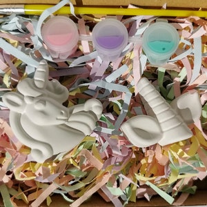Puede incluir: Un kit de pintura DIY con una figura de unicornio de cer&aacute;mica blanca, un cuerno y una oreja. El kit incluye tres botes de pintura en rosa, morado y turquesa, un pincel y confeti de papel de colores. Los art&iacute;culos est&aacute;n empaquetados en una caja de cart&oacute;n.